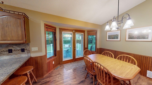 1715 Hansen Dr SW, Willmar, MN 56201 - dining room featuring wainscoting, wood walls, light wood-style floors, and lofted ceiling