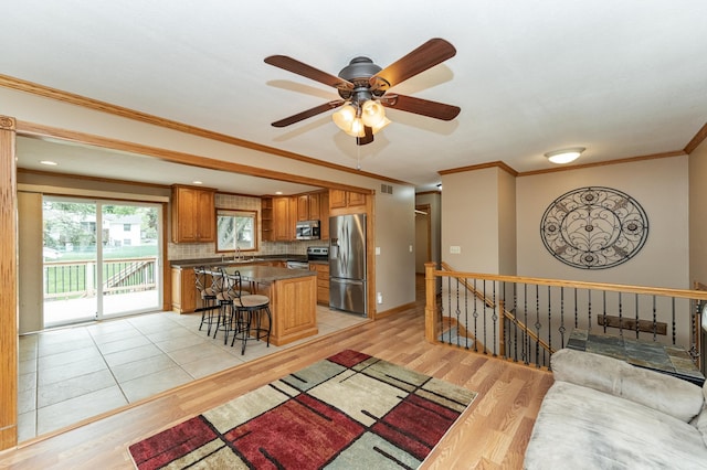222 6th Ave NW, Byron, MN 55920 - kitchen with appliances with stainless steel finishes, light wood-style flooring, a breakfast bar area, brown cabinets, and a center island
