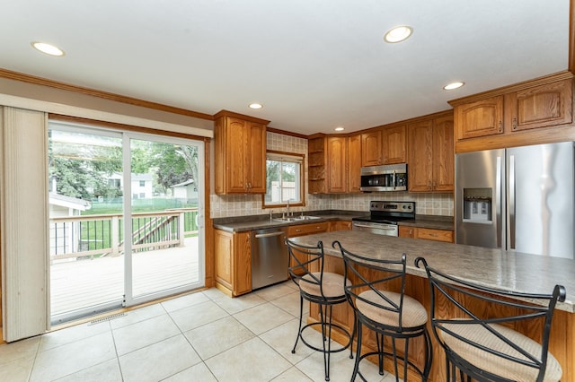 222 6th Ave NW, Byron, MN 55920 - kitchen with stainless steel appliances, dark countertops, a sink, decorative backsplash, and ornamental molding