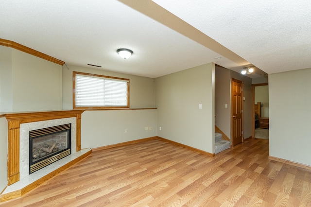 222 6th Ave NW, Byron, MN 55920 - unfurnished living room featuring light wood finished floors, stairway, a fireplace, baseboards, and a textured ceiling