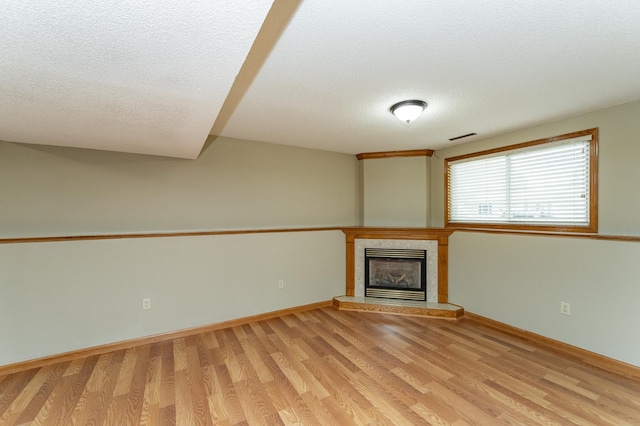 222 6th Ave NW, Byron, MN 55920 - unfurnished living room with a textured ceiling, a glass covered fireplace, light wood-type flooring, and baseboards