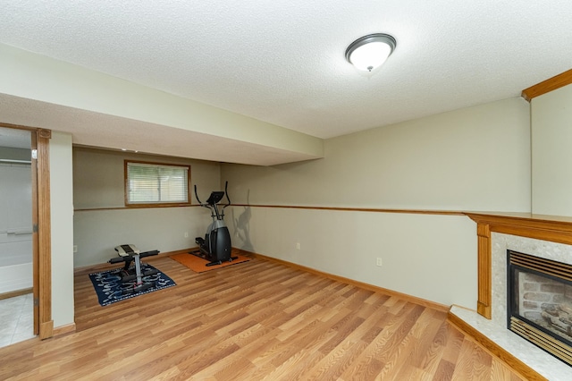 222 6th Ave NW, Byron, MN 55920 - exercise room with light wood-type flooring, a fireplace, a textured ceiling, and baseboards