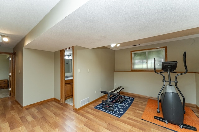 222 6th Ave NW, Byron, MN 55920 - workout room featuring light wood-style floors, a textured ceiling, and baseboards