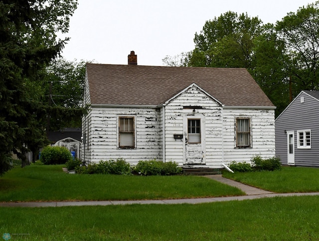 1510 8th St N, Fargo, ND 58102 - view of front facade with a front yard, a chimney, and roof with shingles