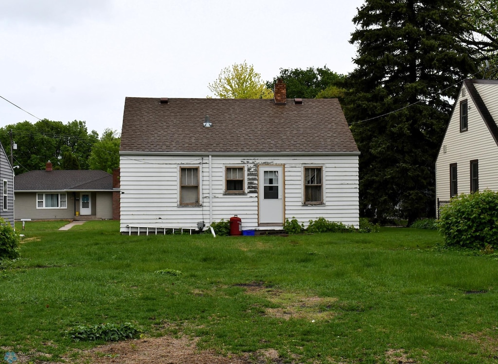 1510 8th St N, Fargo, ND 58102 - rear view of house featuring a chimney, a lawn, and roof with shingles