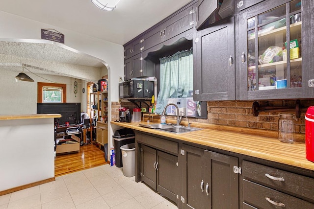 410 Spruce Ave NW, Montgomery, MN 56069 - kitchen featuring a sink, light countertops, tasteful backsplash, black microwave, and arched walkways