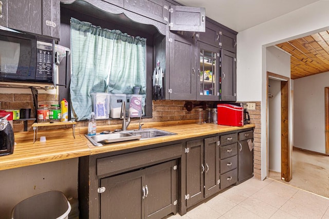 410 Spruce Ave NW, Montgomery, MN 56069 - kitchen with black microwave, a sink, wood ceiling, wooden counters, and light tile patterned floors