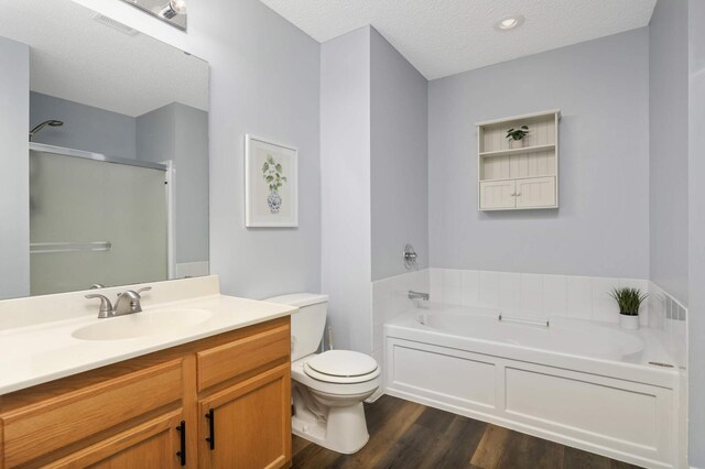 8783 Hastings Cir NE, Blaine, MN 55449 - full bathroom featuring a bath, toilet, wood finished floors, vanity, and a textured ceiling