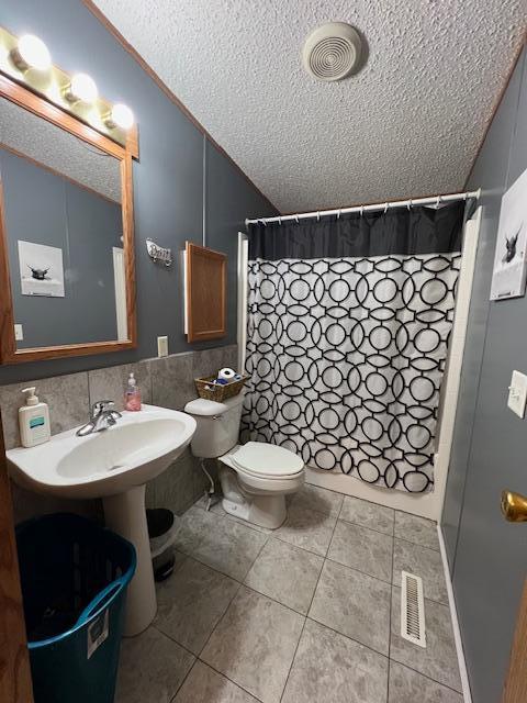 42626 County Highway 125, Perham Twp, MN 56573 - bathroom featuring a textured ceiling, toilet, tile patterned floors, and curtained shower