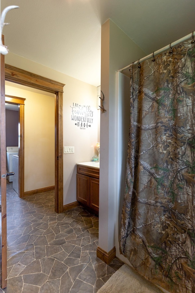 642 4th St, Turtle Lake, WI 54004 - full bathroom featuring stone floors, baseboards, washer / clothes dryer, a shower with shower curtain, and vanity