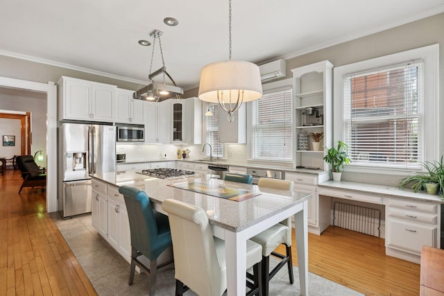 776 Summit Ave, Saint Paul, MN 55105 - kitchen featuring appliances with stainless steel finishes, ornamental molding, a center island, white cabinets, and a breakfast bar