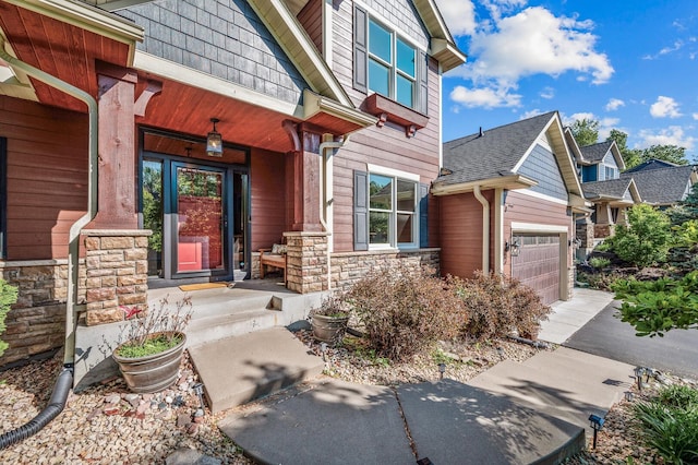 6415 Queensland Ln N, Maple Grove, MN 55311 - entrance to property featuring stone siding, an attached garage, driveway, and covered porch