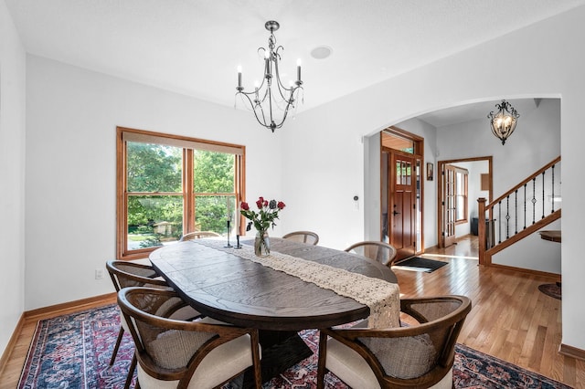 6415 Queensland Ln N, Maple Grove, MN 55311 - dining area featuring a chandelier, arched walkways, wood finished floors, stairway, and baseboards
