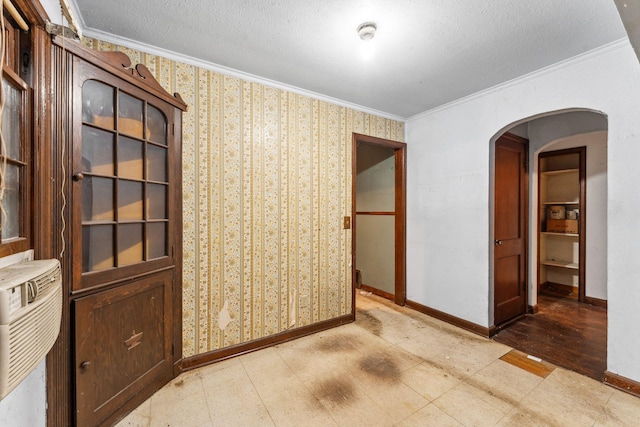 3032 County Road H2, Mounds View, MN 55112 - empty room featuring crown molding, arched walkways, baseboards, wallpapered walls, and a textured ceiling