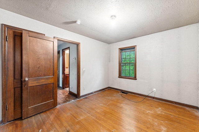 3032 County Road H2, Mounds View, MN 55112 - spare room featuring light wood-type flooring, baseboards, and a textured ceiling