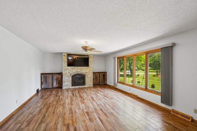 2216 146th Ave NE, Ham Lake, MN 55304 - unfurnished living room with a ceiling fan, wood finished floors, a textured ceiling, and a stone fireplace