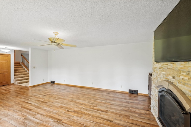 2216 146th Ave NE, Ham Lake, MN 55304 - unfurnished living room featuring ceiling fan, light wood-style floors, stairs, and a textured ceiling