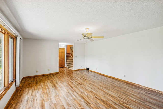 2216 146th Ave NE, Ham Lake, MN 55304 - empty room with stairs, light wood-type flooring, a ceiling fan, and a textured ceiling