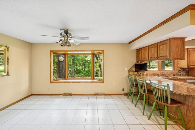 2216 146th Ave NE, Ham Lake, MN 55304 - kitchen featuring plenty of natural light, brown cabinets, light stone counters, ceiling fan, and a textured ceiling