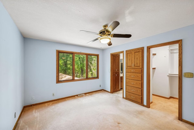 2216 146th Ave NE, Ham Lake, MN 55304 - unfurnished bedroom with light carpet, a walk in closet, a ceiling fan, a closet, and a textured ceiling