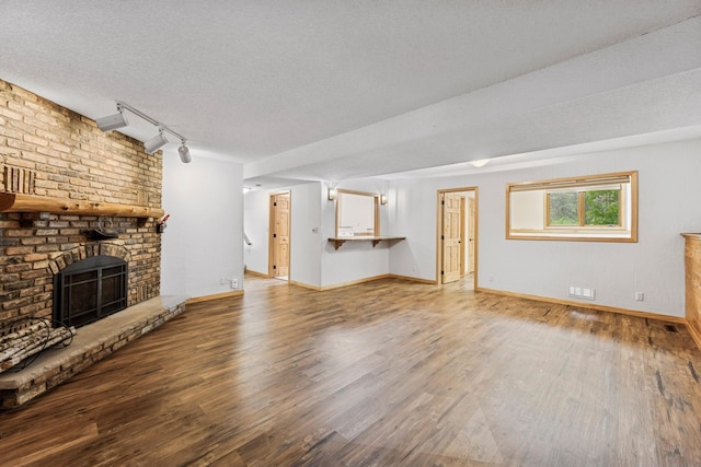 2216 146th Ave NE, Ham Lake, MN 55304 - unfurnished living room featuring track lighting, wood finished floors, a brick fireplace, and a textured ceiling