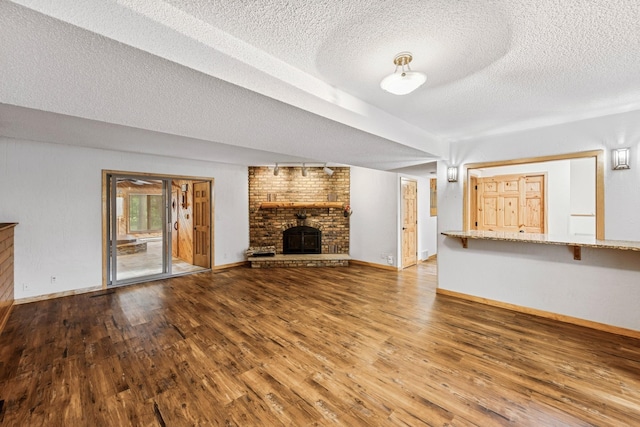 2216 146th Ave NE, Ham Lake, MN 55304 - unfurnished living room featuring a brick fireplace, wood finished floors, and a textured ceiling