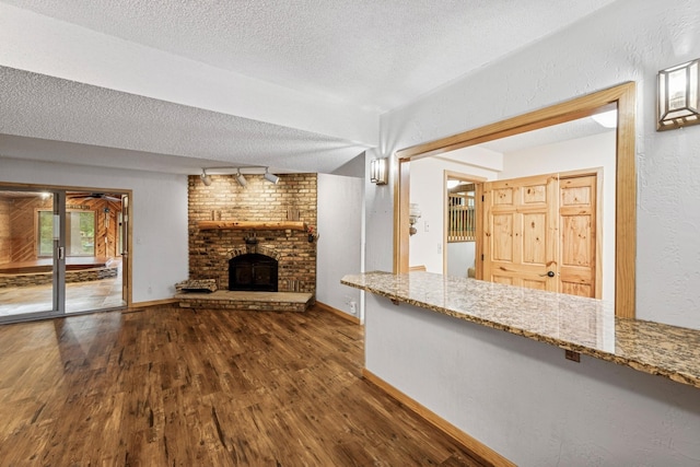 2216 146th Ave NE, Ham Lake, MN 55304 - unfurnished living room with wood finished floors, a textured ceiling, a fireplace, and a textured wall