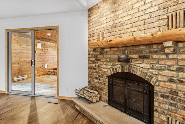 2216 146th Ave NE, Ham Lake, MN 55304 - unfurnished living room featuring wood-type flooring, baseboard heating, and a brick fireplace