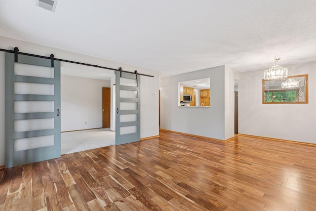 20 Windsor Ln Unit 213A, New Brighton, MN 55112 - unfurnished living room featuring a barn door, wood finished floors, and a chandelier