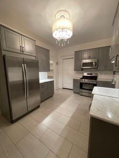 2204 Girard Ave S, Minneapolis, MN 55405 - kitchen with stainless steel appliances, a chandelier, light countertops, and gray cabinetry