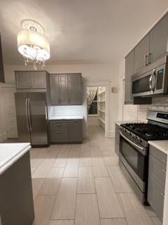 2204 Girard Ave S, Minneapolis, MN 55405 - kitchen featuring appliances with stainless steel finishes, light countertops, decorative backsplash, gray cabinetry, and a chandelier