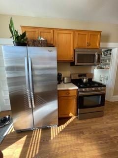 2204 Girard Ave S, Minneapolis, MN 55405 - kitchen featuring stainless steel appliances, brown cabinetry, wood finished floors, and light countertops