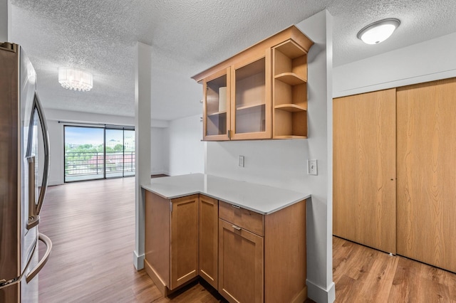 26 10th St W Unit 1108, Saint Paul, MN 55102 - kitchen with freestanding refrigerator, light wood finished floors, light countertops, a textured ceiling, and glass insert cabinets