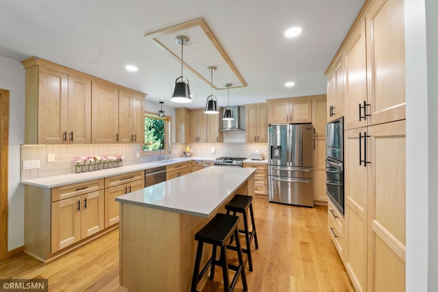2119 13th Ave E, North Saint Paul, MN 55109 - kitchen featuring appliances with stainless steel finishes, light brown cabinetry, wall chimney exhaust hood, a breakfast bar, and tasteful backsplash