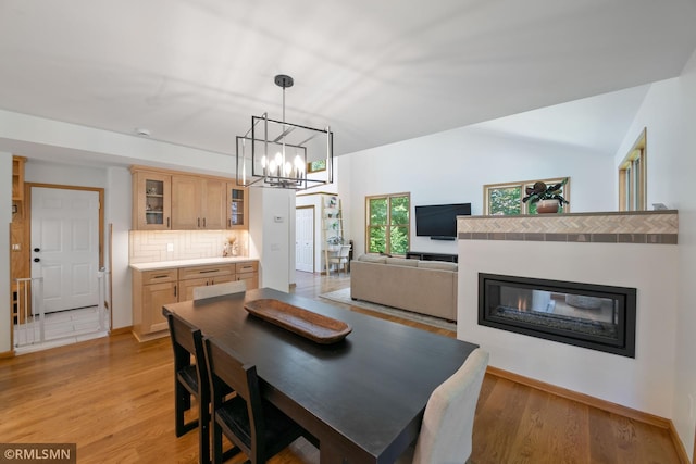 2119 13th Ave E, North Saint Paul, MN 55109 - dining space with light wood-type flooring, a chandelier, and a glass covered fireplace