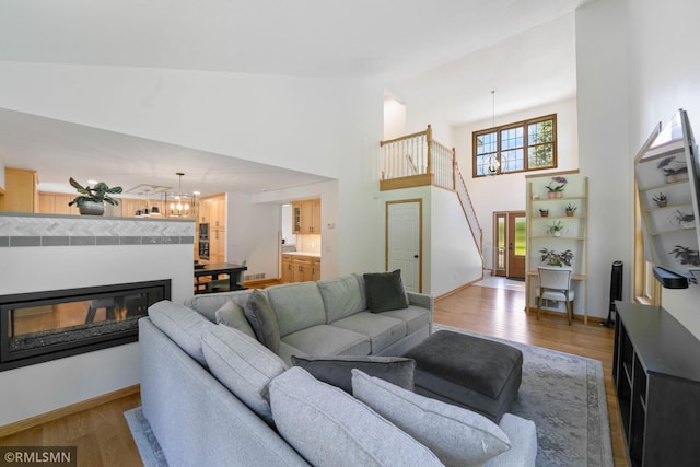 2119 13th Ave E, North Saint Paul, MN 55109 - living area with wood finished floors, a chandelier, high vaulted ceiling, and a glass covered fireplace