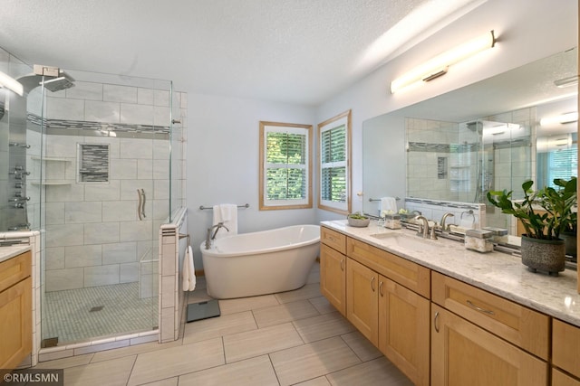 2119 13th Ave E, North Saint Paul, MN 55109 - bathroom with vanity, a stall shower, a freestanding tub, a textured ceiling, and tile patterned flooring