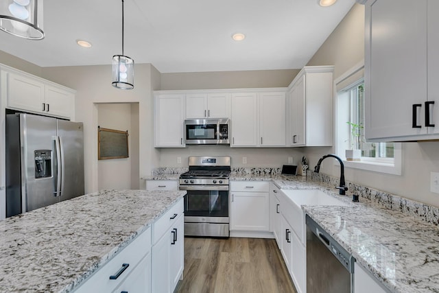1715 Par Ln, Buffalo, MN 55313 - kitchen with appliances with stainless steel finishes, a sink, white cabinetry, light wood-type flooring, and light stone counters
