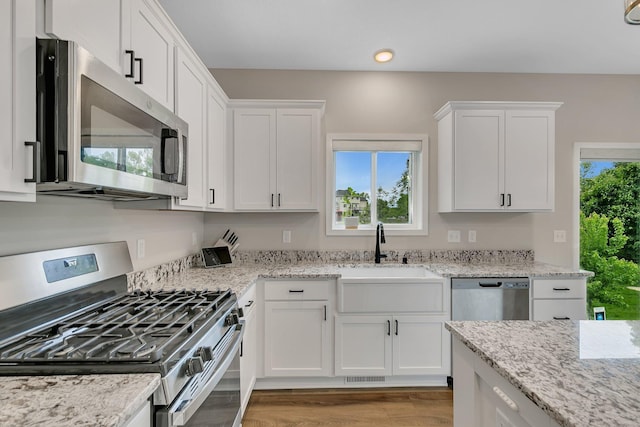 1715 Par Ln, Buffalo, MN 55313 - kitchen featuring appliances with stainless steel finishes, a sink, white cabinetry, light wood finished floors, and recessed lighting