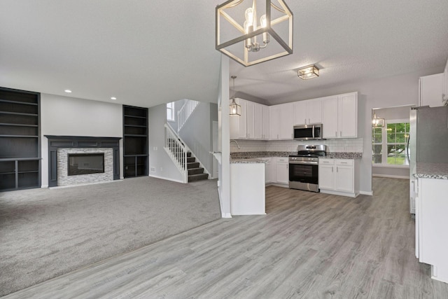 1418 Bluff St, Dundas, MN 55019 - kitchen featuring stainless steel appliances, open floor plan, white cabinets, light wood-style floors, and light stone counters