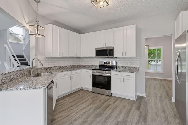 1418 Bluff St, Dundas, MN 55019 - kitchen featuring appliances with stainless steel finishes, light wood-style flooring, white cabinets, light stone counters, and a textured ceiling