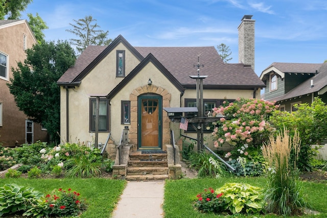 241 Queen Ave S, Minneapolis, MN 55405 - tudor house with stucco siding, a chimney, roof with shingles, and entry steps