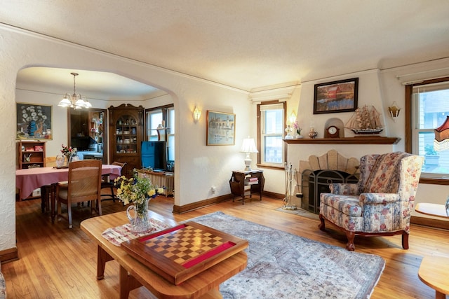 241 Queen Ave S, Minneapolis, MN 55405 - living room with arched walkways, wood finished floors, a brick fireplace, a chandelier, and crown molding