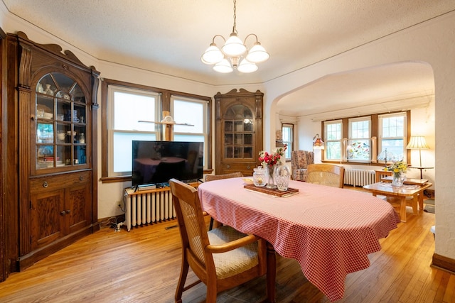 241 Queen Ave S, Minneapolis, MN 55405 - dining area with arched walkways, radiator, a chandelier, and light wood-style flooring