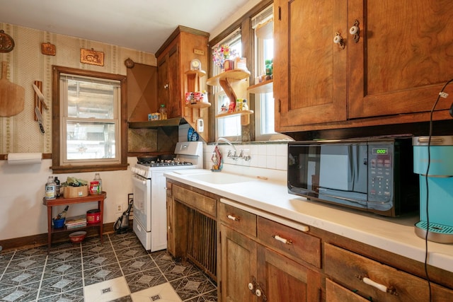 241 Queen Ave S, Minneapolis, MN 55405 - kitchen featuring white gas range, black microwave, a sink, brown cabinetry, and light countertops