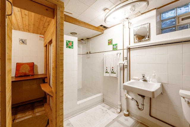 241 Queen Ave S, Minneapolis, MN 55405 - bathroom featuring tile walls, a tile shower, a sink, toilet, and tile patterned floors