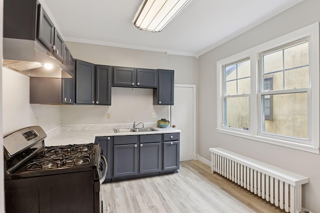1418 Payne Ave, Saint Paul, MN 55130 - kitchen with gas range oven, radiator, under cabinet range hood, light countertops, and light wood finished floors