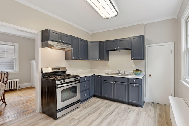 1418 Payne Ave, Saint Paul, MN 55130 - kitchen with gas stove, under cabinet range hood, light countertops, light wood-style flooring, and radiator
