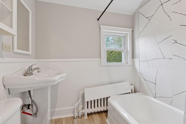 1418 Payne Ave, Saint Paul, MN 55130 - full bathroom featuring radiator heating unit, wainscoting, a bath, and wood finished floors