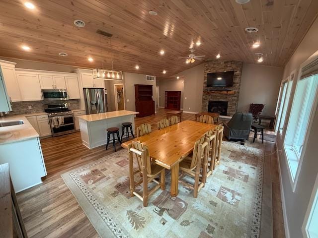 6207 Lagoon Dr NE, Bemidji, MN 56601 - dining room featuring a stone fireplace, light wood finished floors, lofted ceiling, a ceiling fan, and plenty of natural light